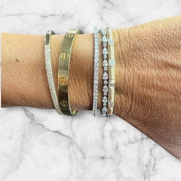The Karat Concierge emerald cut fluted diamond bangle worn on a wrist with stacked gold and diamond bracelets.