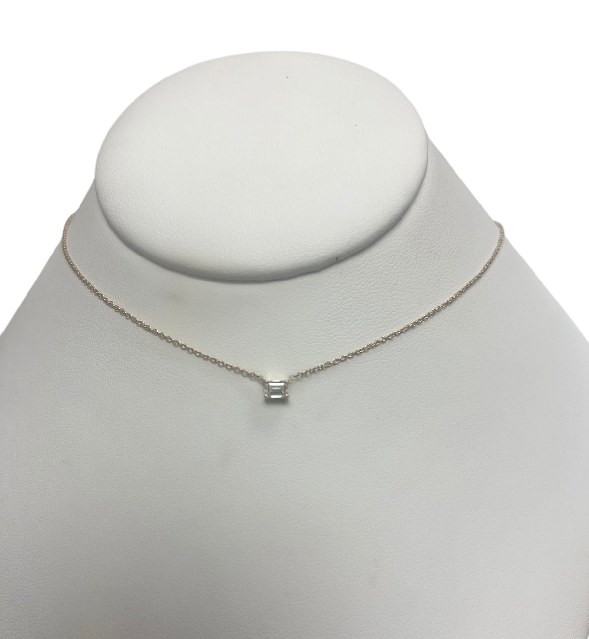 The Karat Concierge emerald cut solitaire diamond necklace on a delicate 14K yellow gold chain.