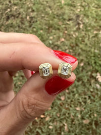 The Karat Concierge Gatsby emerald cut diamond stud earrings in 14K yellow gold with faceted bezel settings.