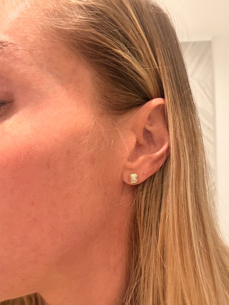 The Karat Concierge Gatsby Stud emerald diamond earrings in 14K yellow gold worn on a woman's earlobe.