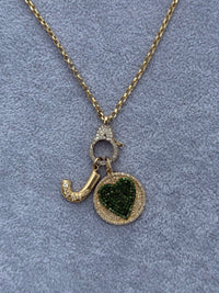 The Karat Concierge round pendant featuring a pavé emerald heart, diamond accents, and a gold chain with a push lock.