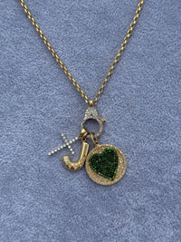 The Karat Concierge round emerald heart pendant with diamond accents on a 14K yellow gold chain with charms