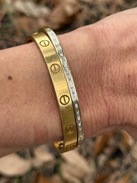 The Karat Concierge yellow gold screw-motif bangle stacked with a channel-set baguette diamond bangle on a wrist.