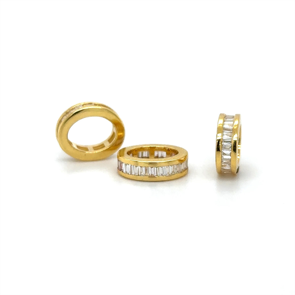 The Karat Concierge 14K yellow gold oval bangle rondelles with channel set baguette diamonds on a white background