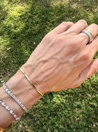 The Karat Concierge Bar Twelve Bracelet in 14K yellow gold with geometric bar links worn on a wrist with other jewelry