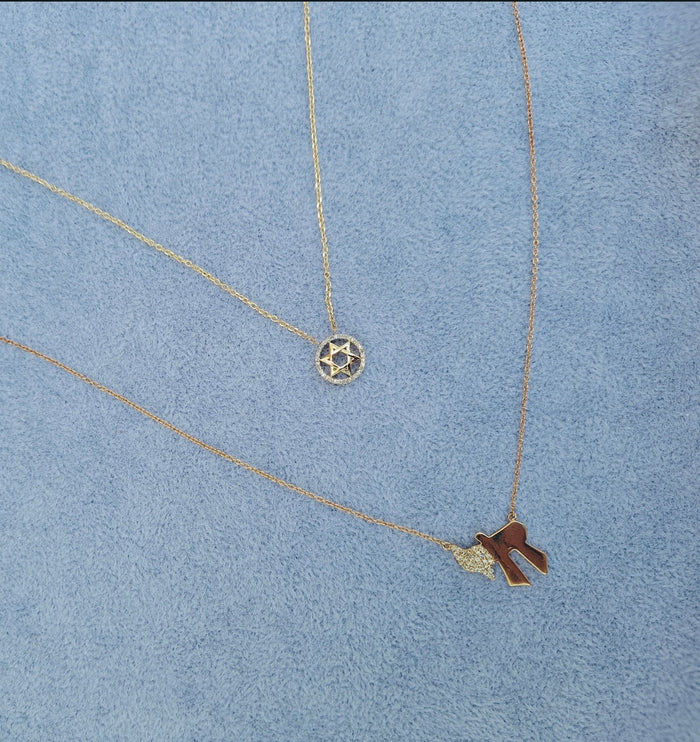 The Karat Concierge 14K yellow gold Chai necklace with pavé diamonds on a delicate chain against a blue background.