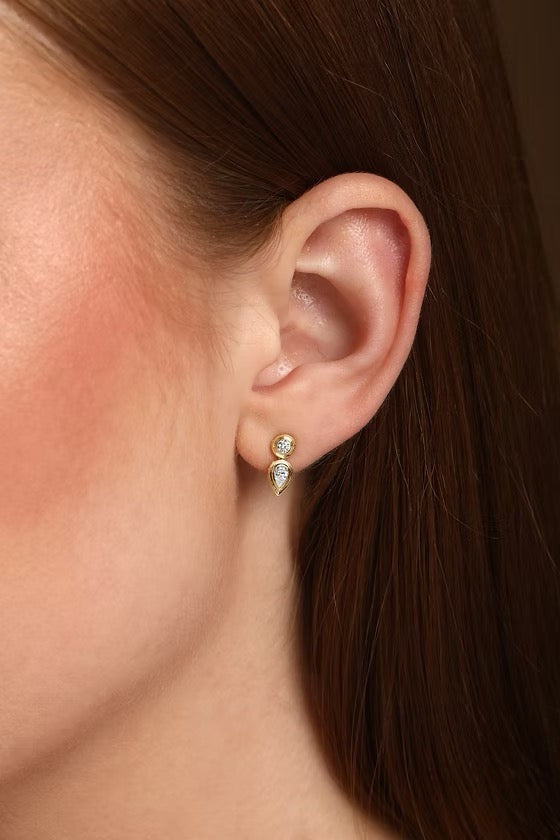 The Karat Concierge Gatsby drop earrings featuring a round and pear-shaped diamond in 14K gold worn on an earlobe.