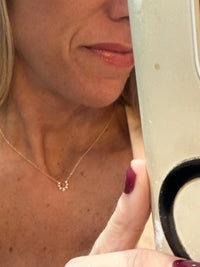 The Karat Concierge 14K gold horseshoe necklace with seven graduated diamonds worn on a woman's neck