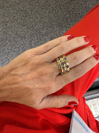 The Karat Concierge 14KT yellow gold donut rings stacked on a finger featuring oval emerald, ruby, and sapphire stones.