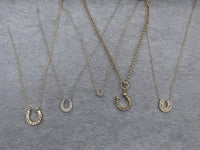 The Karat Concierge Fortuna Pave Horseshoe Necklace collection featuring various 14K yellow gold diamond pendants.