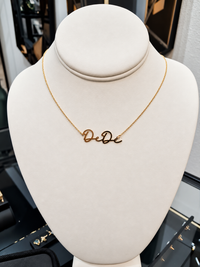 The Karat Concierge custom name necklace in 14K yellow gold with elegant script lettering on a display bust.
