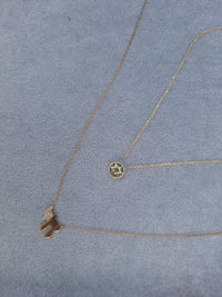 The Karat Concierge 14K yellow gold Star of David necklace with diamond accents on a light blue velvet background