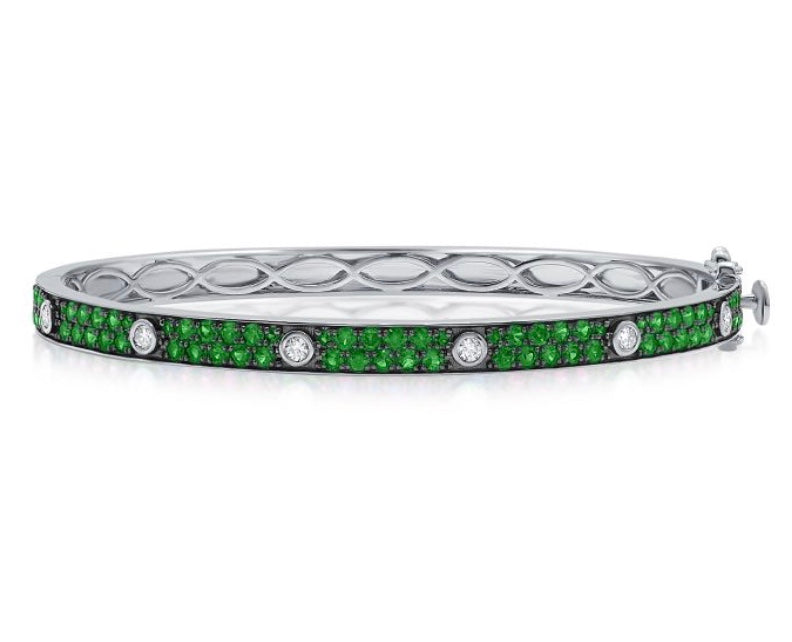 The Karat Concierge Pave Muse bangle in white gold with green gemstones and bezel-set diamonds.