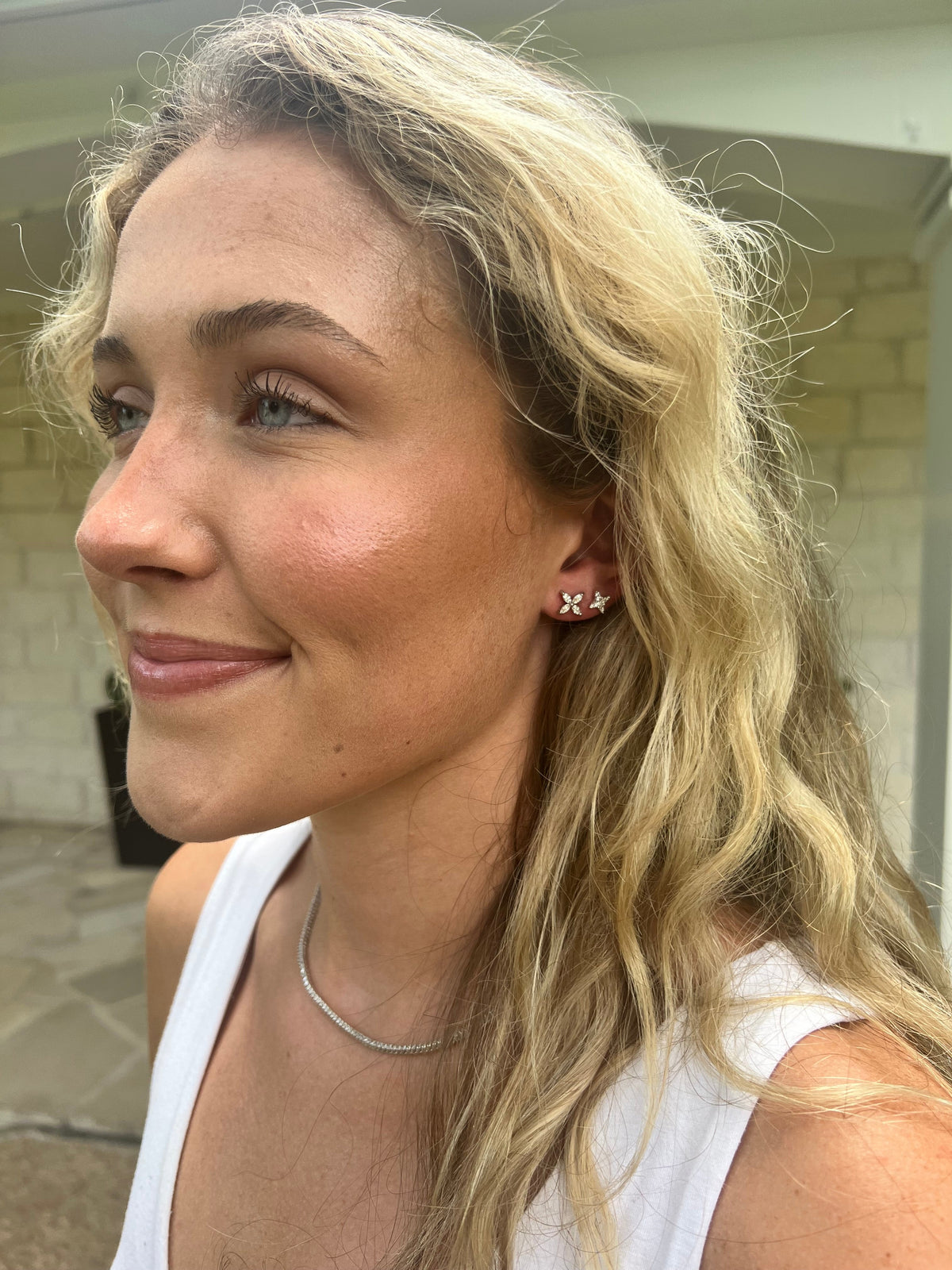 The Karat Concierge Hannah star stud earrings in 14K yellow gold with natural diamonds worn by a blonde woman