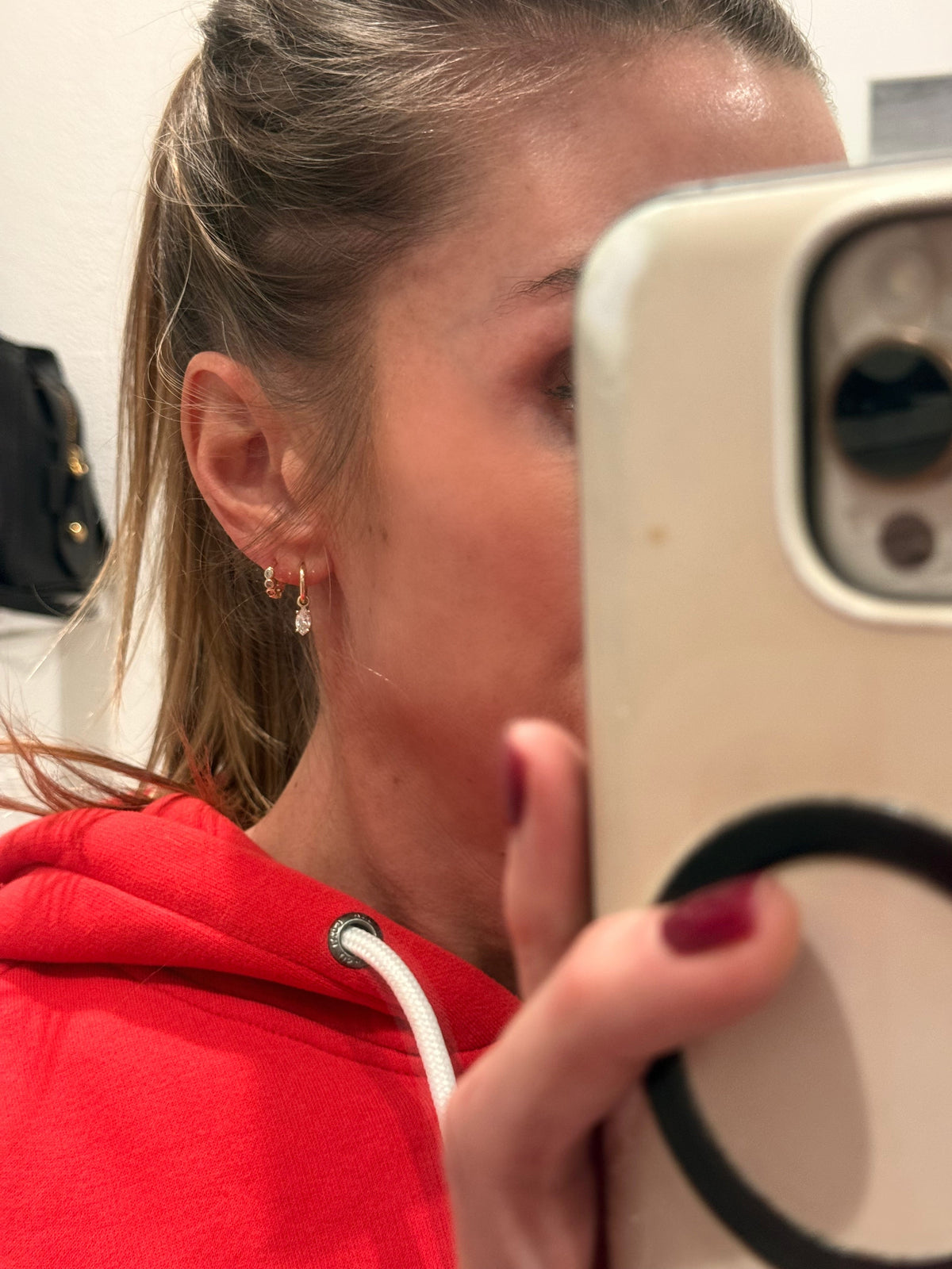 The Karat Concierge marquise diamond drop huggie earrings in 14K yellow gold worn on a woman's ear