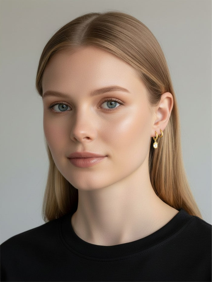 The Karat Concierge marquise diamond drop huggie earrings in 14K yellow gold worn by a woman with blonde hair.
