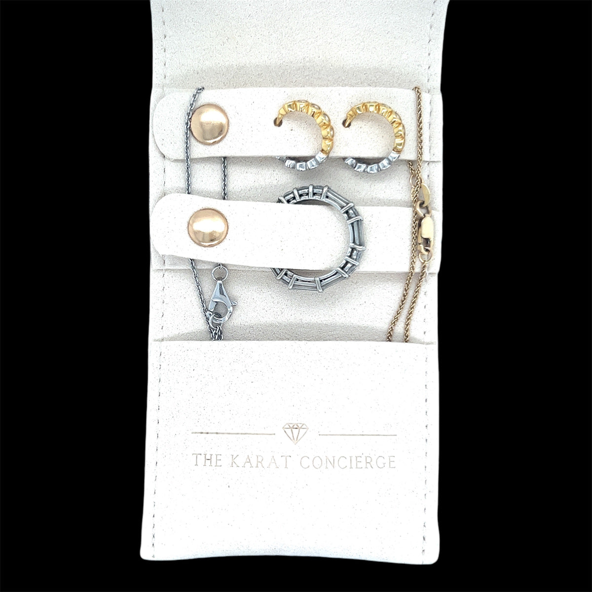 The Karat Concierge mini travel jewelry case in cream suede with gold and silver earrings and rings inside.