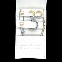 The Karat Concierge mini travel jewelry case in cream suede with gold and silver earrings and rings inside.