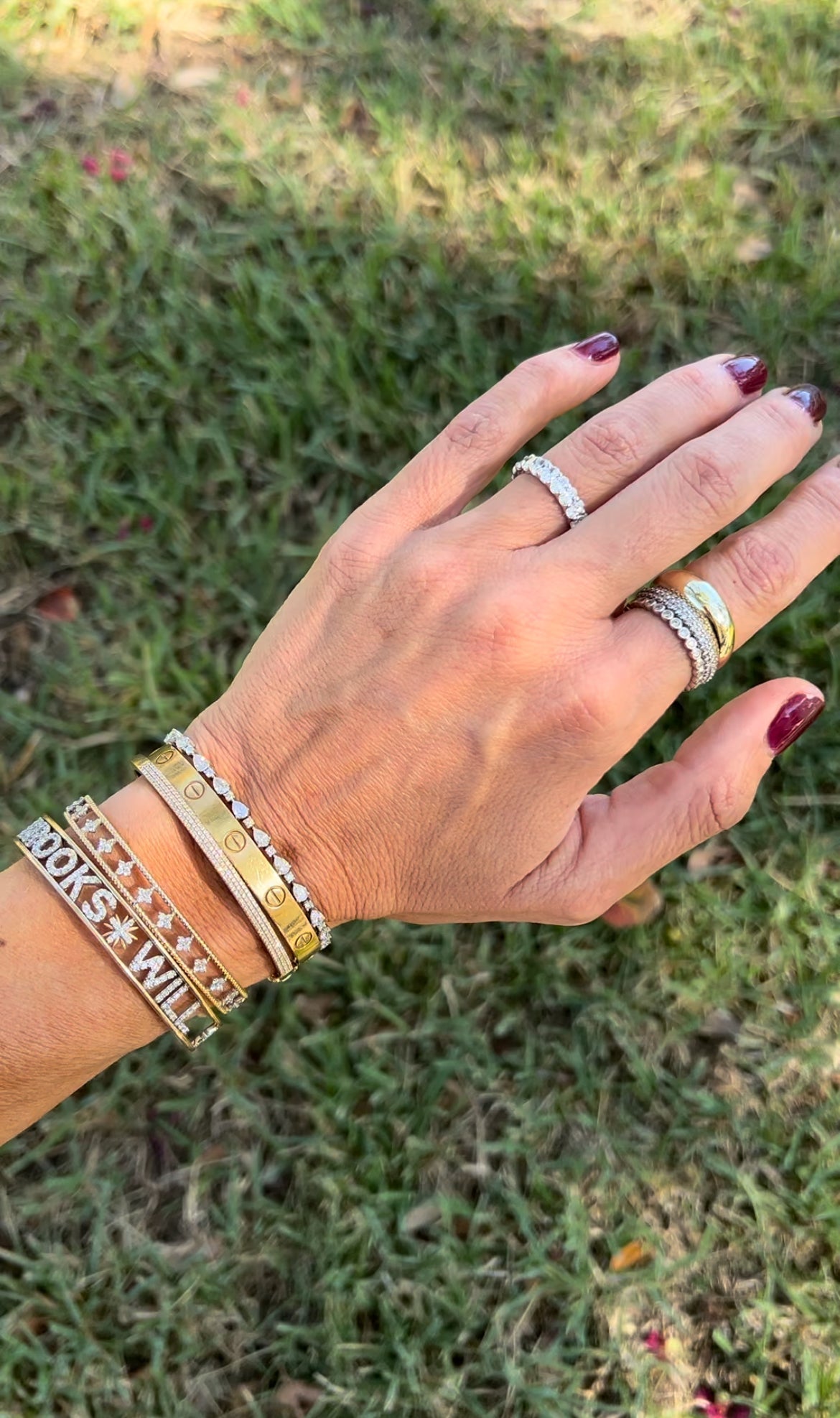 The Karat Concierge oval lab grown diamond eternity band worn on a finger with stacked gold and diamond bracelets.