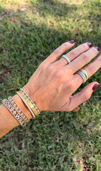 The Karat Concierge oval lab grown diamond eternity band worn on a finger with stacked gold and diamond bracelets.