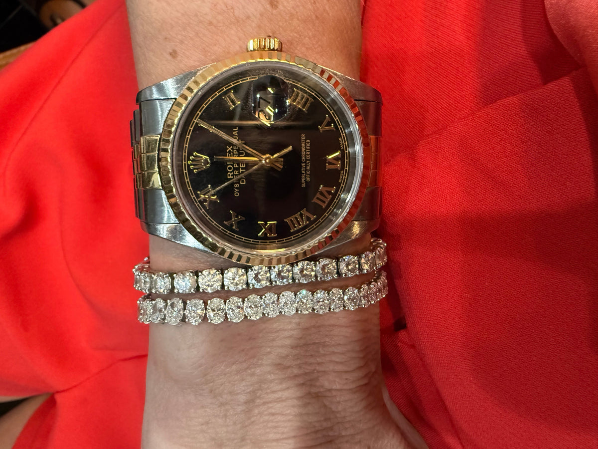 The Karat Concierge oval diamond tennis bracelet in 14K white gold worn on a wrist with a two-tone luxury watch.