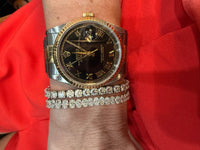 The Karat Concierge oval diamond tennis bracelet in 14K white gold worn on a wrist with a two-tone luxury watch.