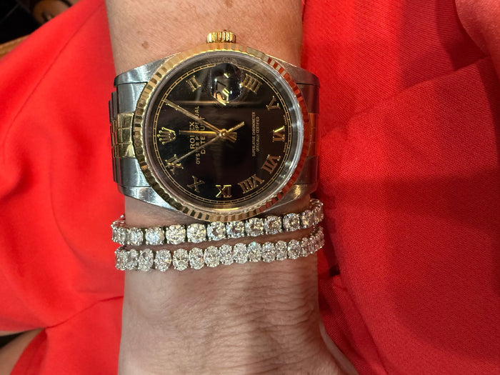 The Karat Concierge oval diamond tennis bracelet in 14K white gold worn on a wrist with a two-tone luxury watch.