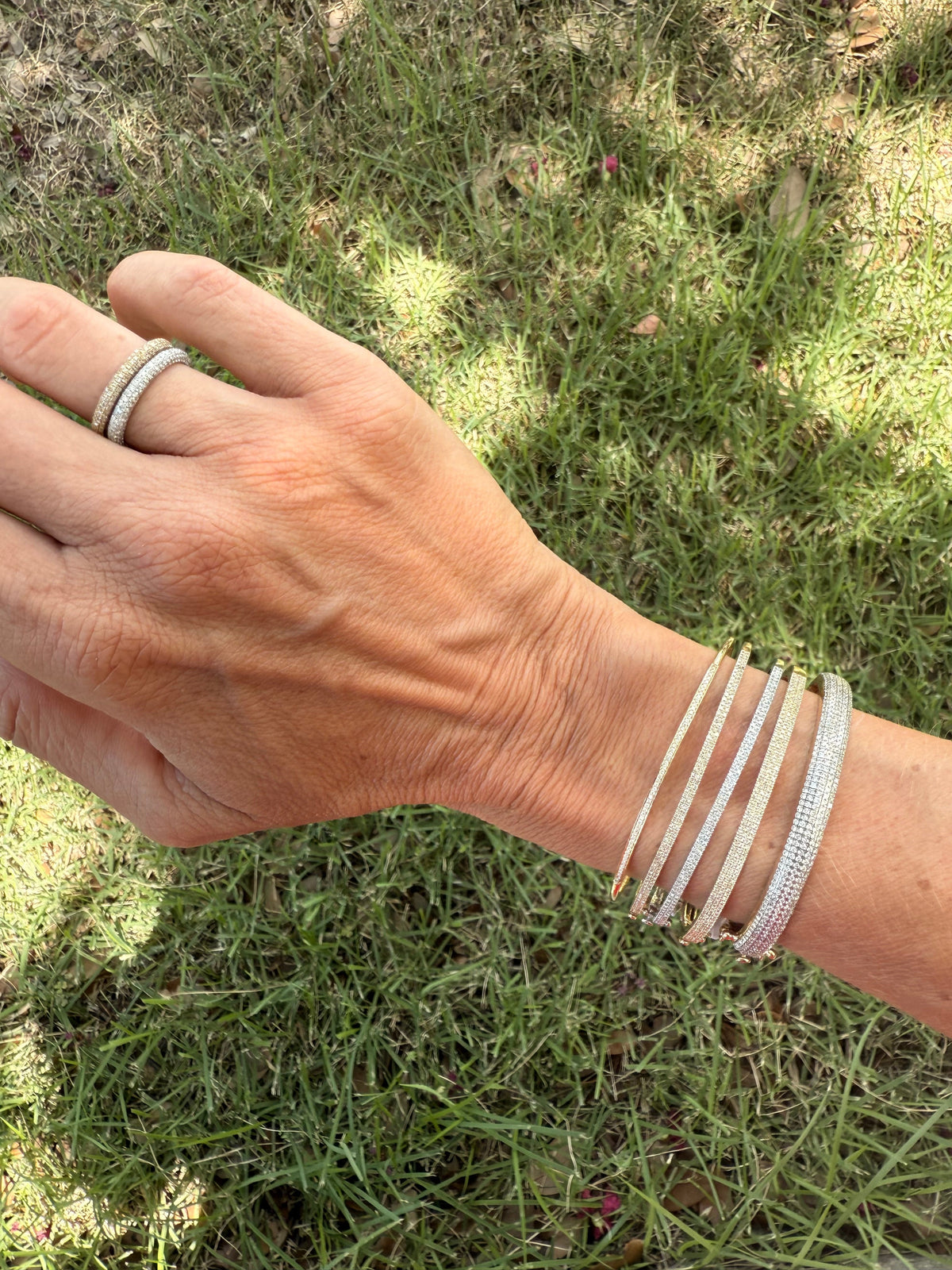 The Karat Concierge pave eternity bands and diamond bracelets in white and yellow gold worn on a woman's wrist.
