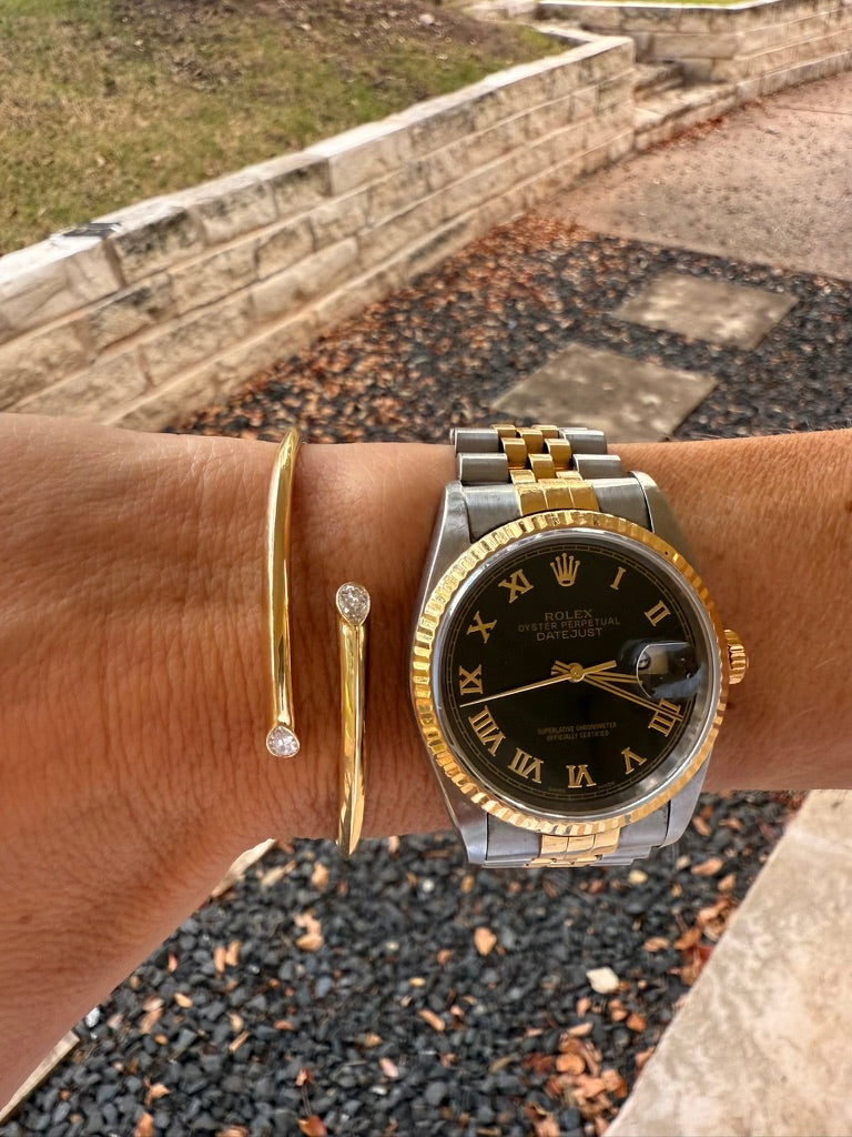 The Karat Concierge 14K yellow gold hinged cuff bangle with two pear-shaped bezel-set diamonds worn on a wrist.