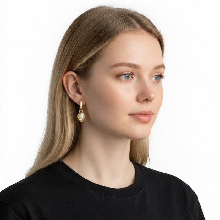 Model wearing The Karat Concierge Gatsby pear-shaped huggie earrings in 14K yellow gold with diamond bezels.