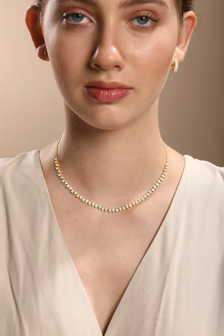 The Karat Concierge Meridian pear-shaped diamond tennis necklace in 14K yellow gold worn by a woman.
