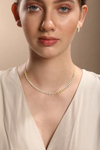 The Karat Concierge Meridian pear-shaped diamond tennis necklace in 14K yellow gold worn by a woman.