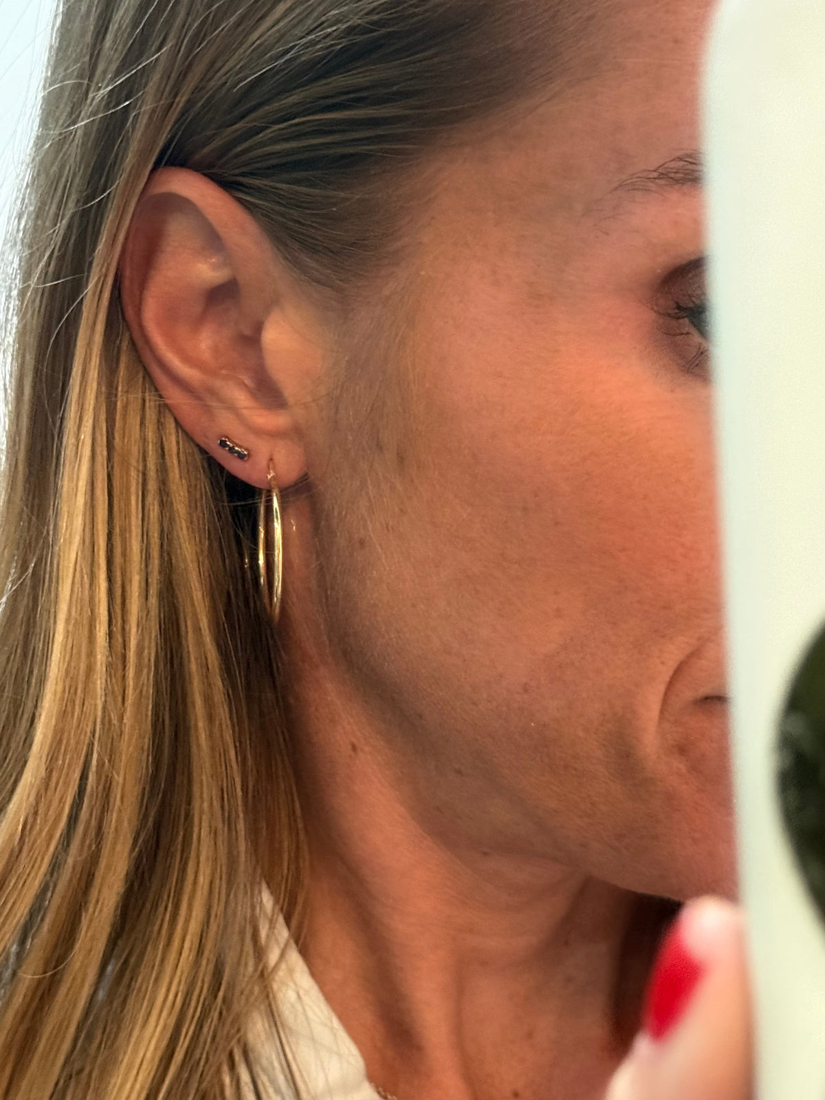 The Karat Concierge 14K yellow gold curved bar earrings featuring three round blue sapphires worn on an earlobe.