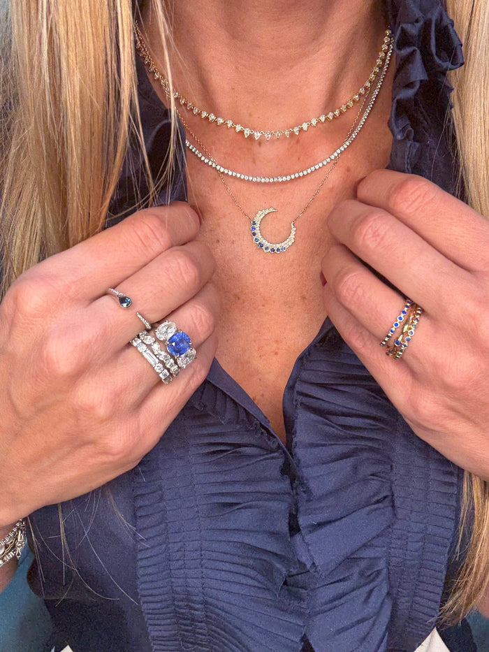 The Karat Concierge 14KT yellow gold crescent moon necklace with diamonds and sapphires layered on a woman