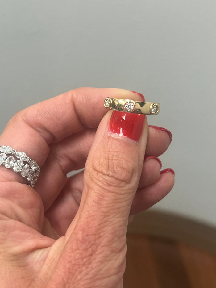 The Karat Concierge 14K yellow gold band featuring three bezel-set floating diamonds held by a hand with red nails.