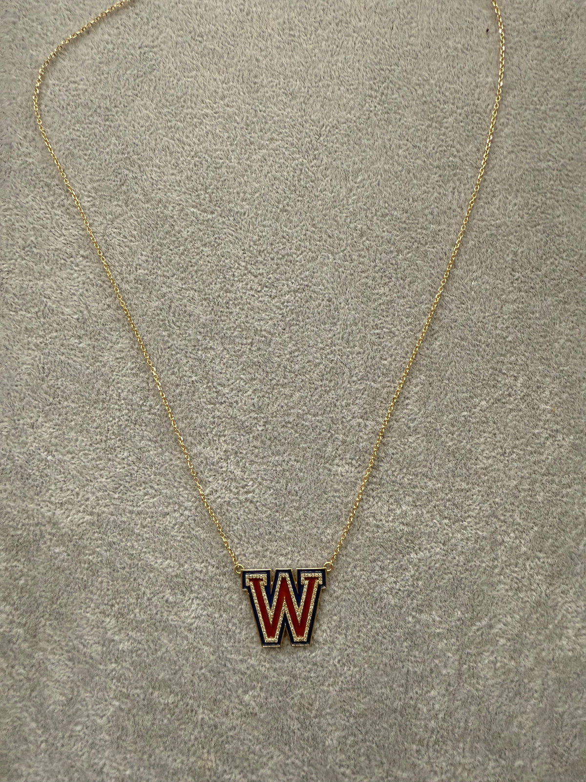 The Karat Concierge Westlake W necklace in yellow gold with red and blue enamel and sparkling diamond accents.