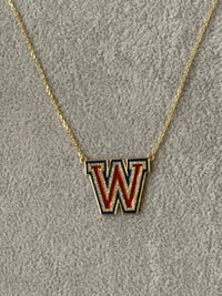 The Karat Concierge Westlake W necklace in yellow gold with red and blue enamel and sparkling diamond accents.
