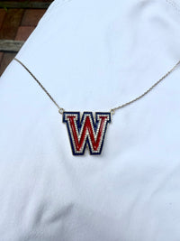 The Karat Concierge Westlake W necklace in white gold with red and blue enamel and sparkling diamond accents.