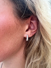 The Karat Concierge Myra 14K white gold huggie earrings featuring pave-set natural diamonds worn on an earlobe