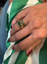 The Karat Concierge 14KT yellow gold ring with a 1.50-carat emerald in a bezel setting worn on a woman's hand.